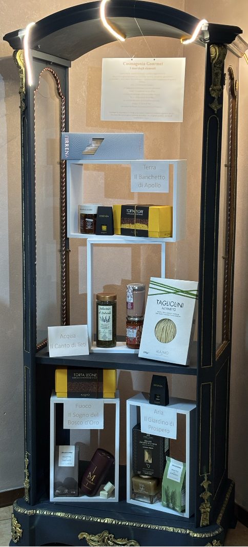 Display window featuring the four element-themed gourmet boxes: Il Giardino di Prospero, Il Sogno del Bosco d’Oro, Il Banchetto di Apollo, and Il Canto di Teti.