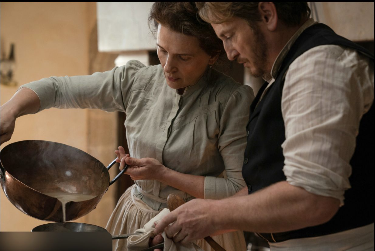 A shared kitchen scene in the film The Taste of Things, where two people prepare a dish together.